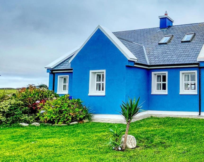 a blue house with a palm tree in the yard at Gemütliches Cottage mit atemberaubender Aussicht in An Geata Mór
