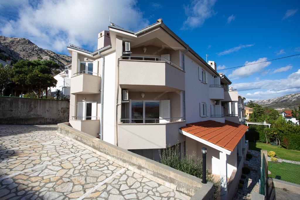 a white apartment building with a stone driveway at Apartments Crnekovic I Zarok in Ba&scaron;ka