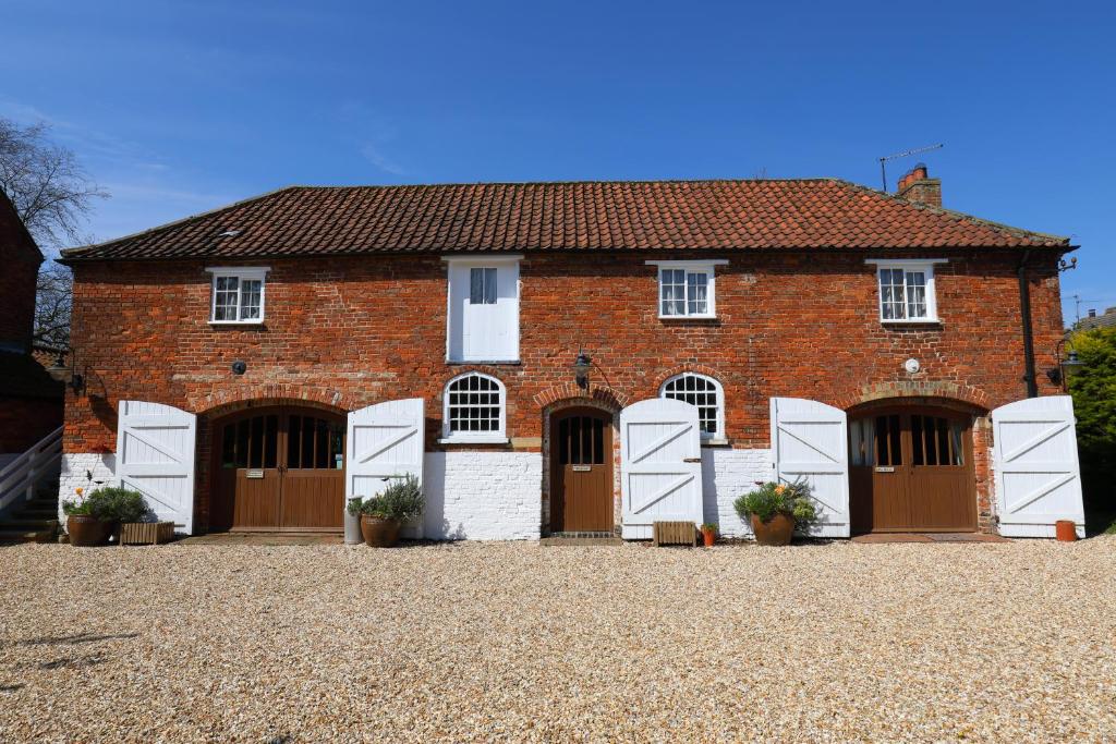 a red brick house with white doors and windows at The Hayloft and Bothy at the Manor House Stables - TWO units in Martin near Woodhall Spa - Dogs Welcome! in Martin