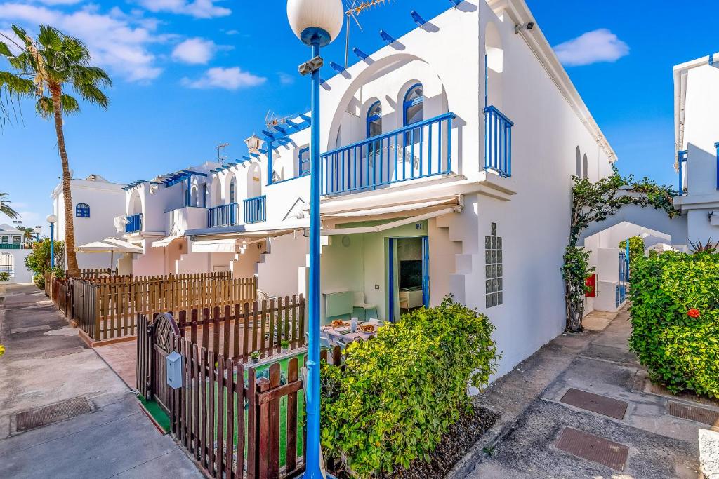 uma casa branca com uma cerca e palmeiras em Duplex Poolside Playa del Ingles em Playa del Inglés