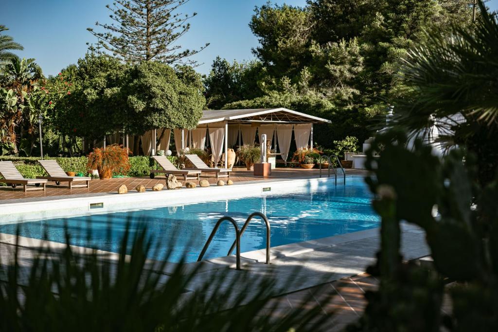 a swimming pool with chairs and a gazebo at Villa Margherita Residence in Favignana