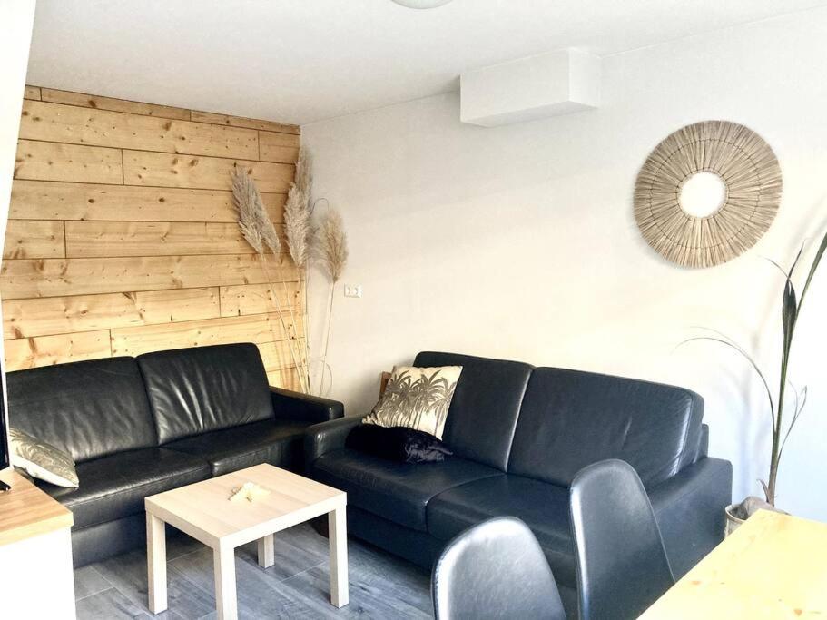 een woonkamer met een zwarte bank en een tafel bij Cosy beach house for ocean & nature lovers in Noordwijk