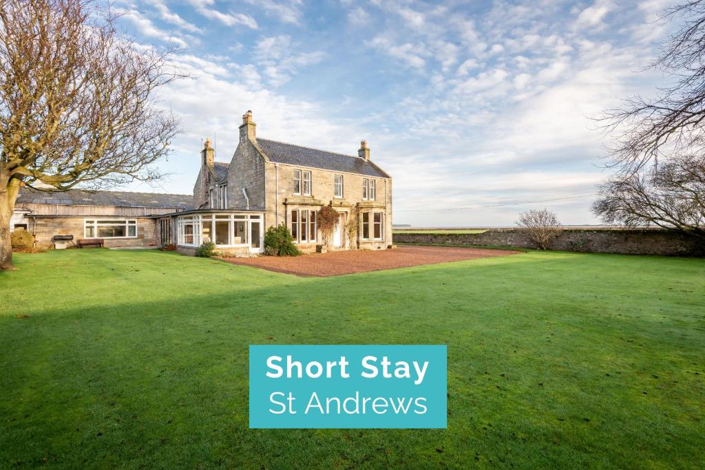 una casa grande en un césped con las palabras "estancia corta" st annhews en Easter Kincaple Farmhouse, Sleeps 16, St Andrews, en St Andrews