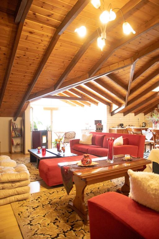 a living room with red couches and a wooden ceiling at Soffitta House Sofi! in Florina