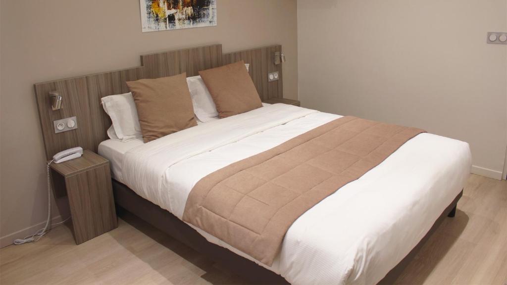 a bedroom with a large bed with a wooden headboard at Hotel Puy De Dôme in Paris