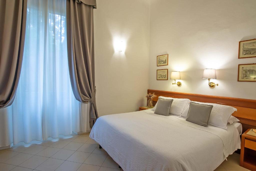 a bedroom with a white bed and a large window at Hotel Bonifacio in Florence