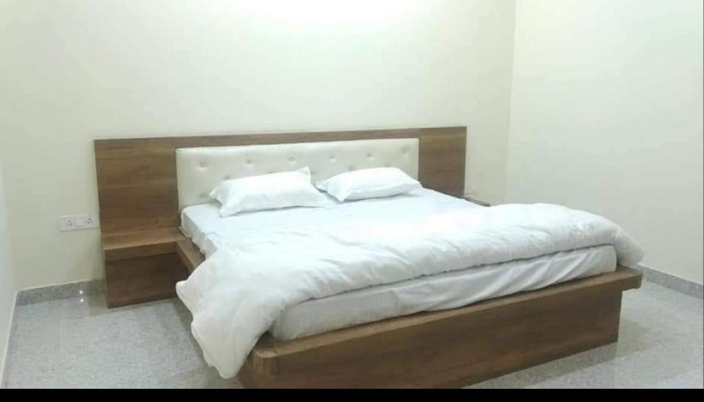 uma cama com lençóis brancos e almofadas em Anant Royal em Govardhan