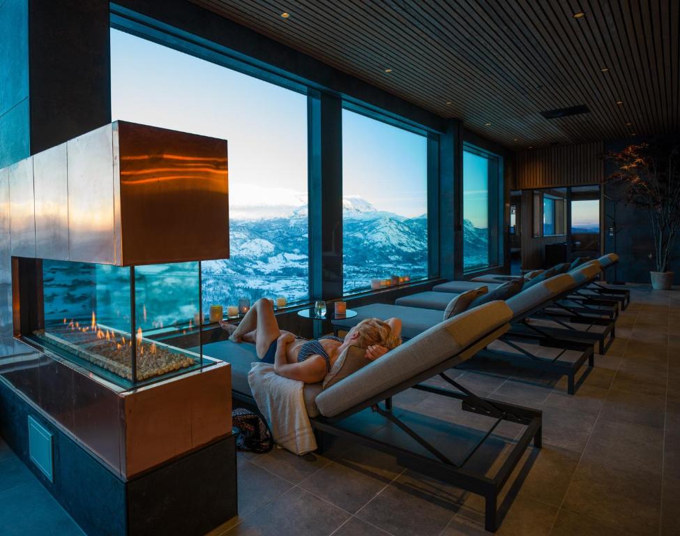 a woman laying on a couch in a room with windows at Skarsnuten Mountain Resort & SPA in Hemsedal
