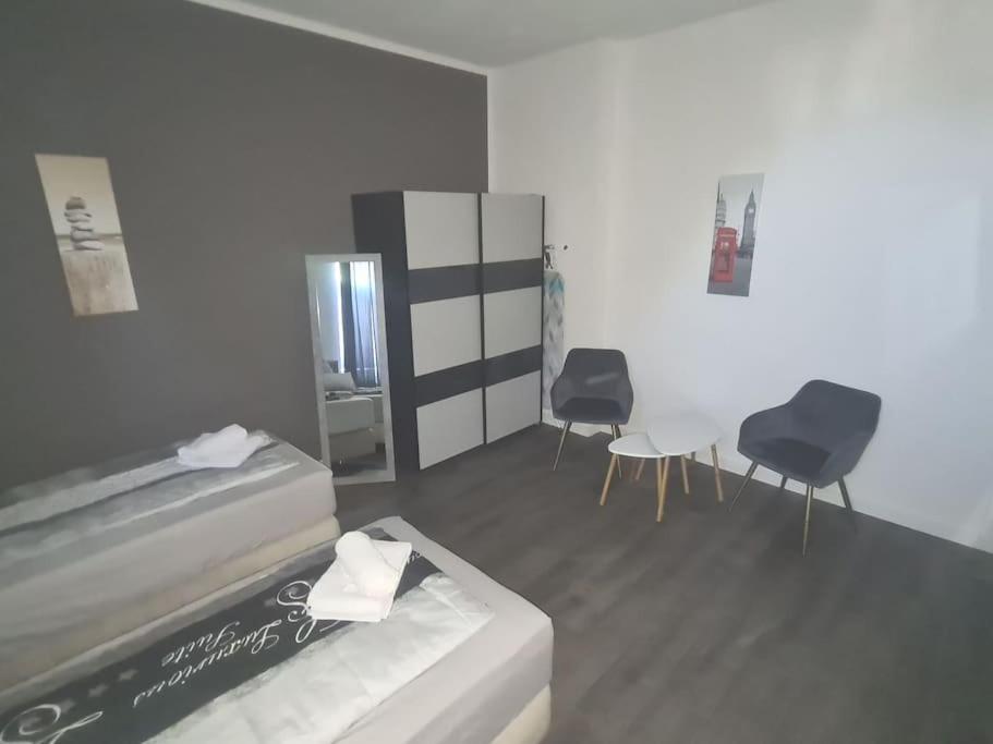 1 Schlafzimmer mit 2 Betten, 2 Stühlen und einem Tisch in der Unterkunft Apartament Suite 2 in Bernburg