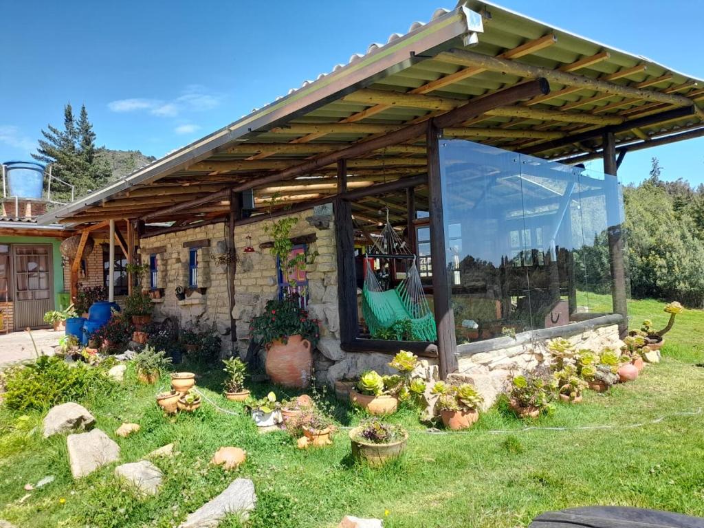 um jardim com um edifício de pedra com uma pérgola em Hotel Rural Granja Agroecoturistica Santa Barbara em Simijaca