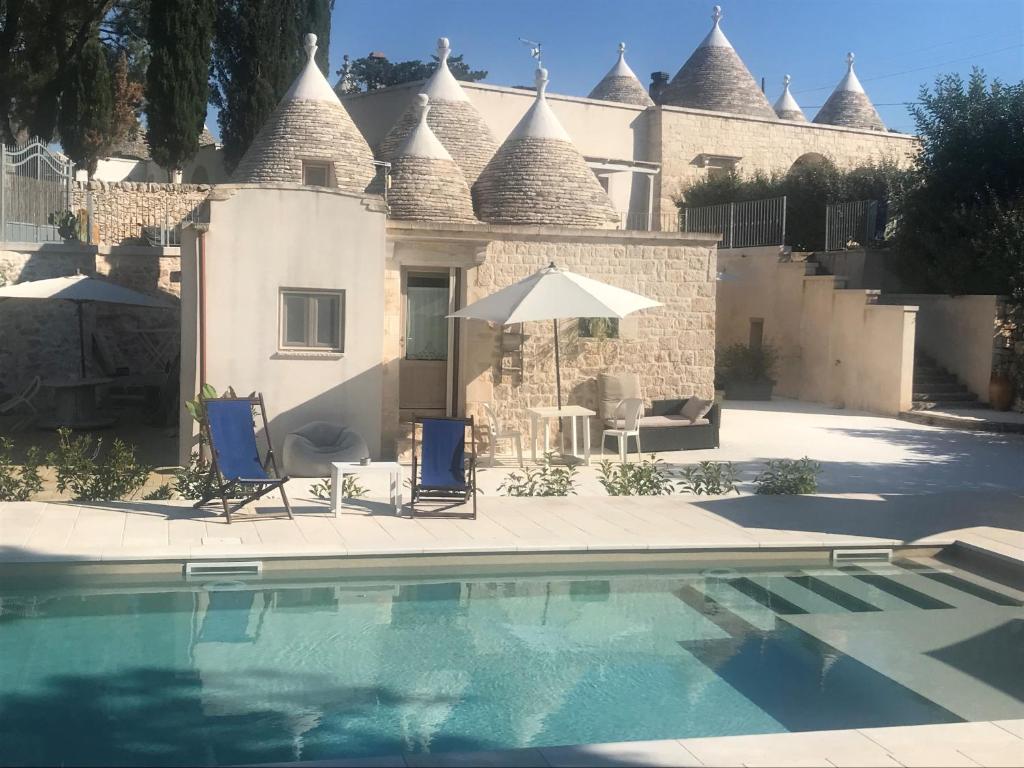 uma casa com piscina e duas cadeiras e um guarda-sol em Pignarè em Locorotondo