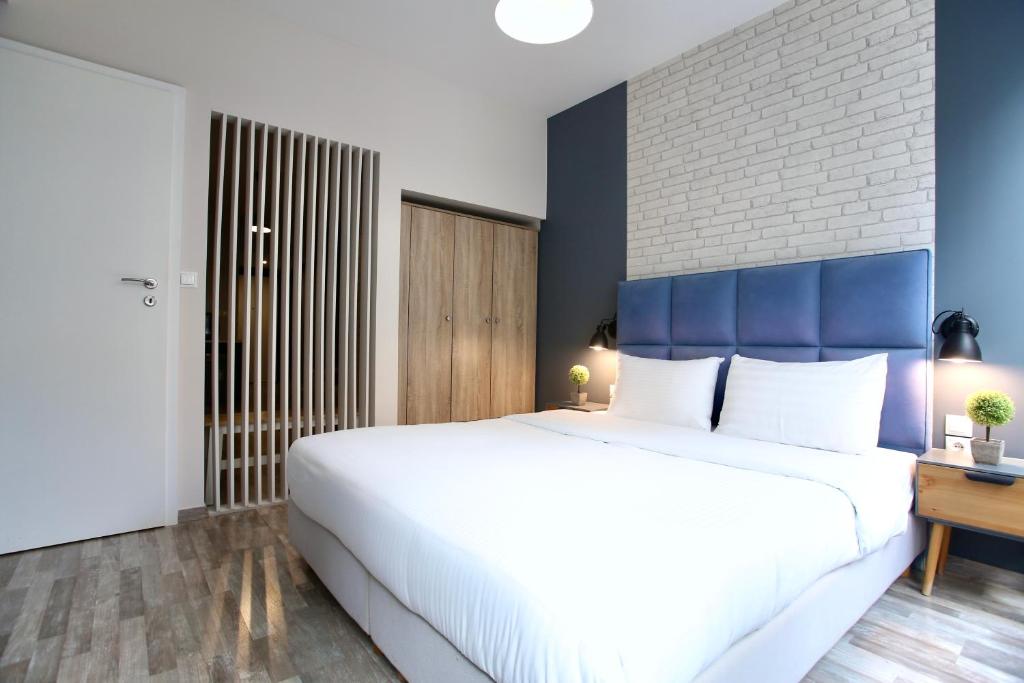 a bedroom with a large white bed with a blue headboard at GK Ermou Str in Athens