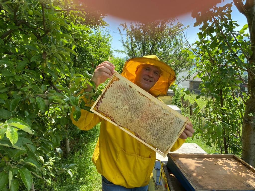 a man in a bee suit holding up a beehive at Zlatna koliba Namir Zuka in Fojnica