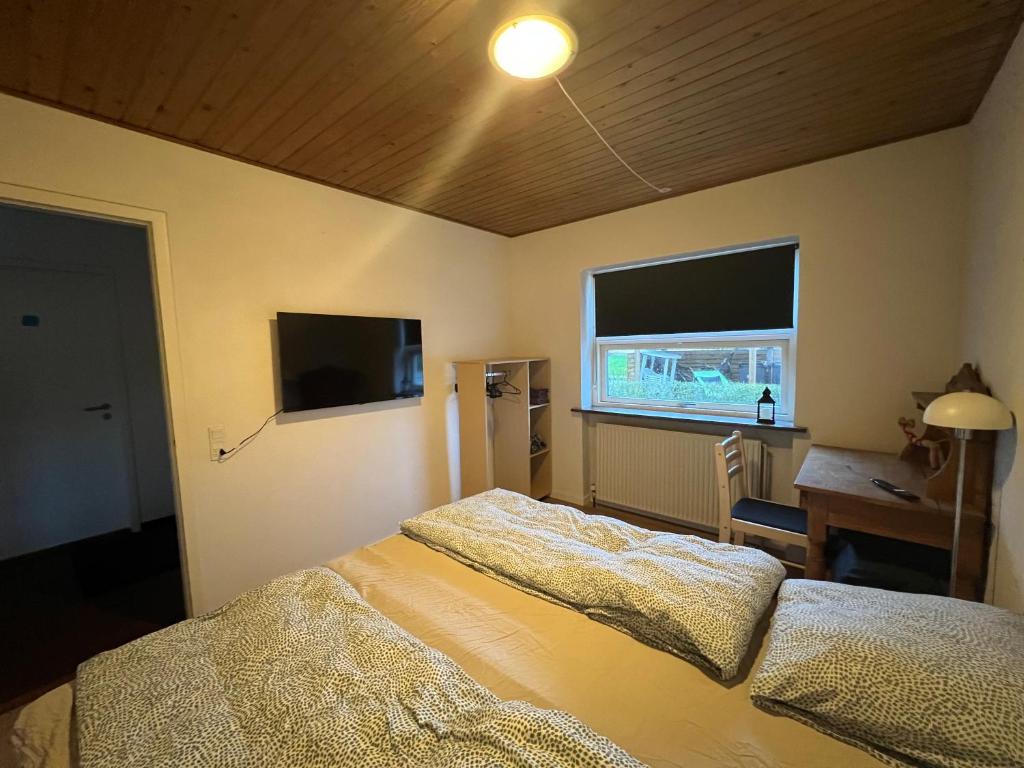 um quarto com uma cama, uma secretária e uma janela em Private fully functional apartment in a villa near forrest em Sonderborg