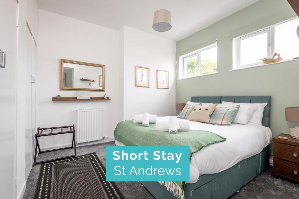 Un dormitorio con una cama y ventanas verdes y blancas. en The Loft on the Lane - 2 Beds - Garden - 5 mins to harbour, en Crail