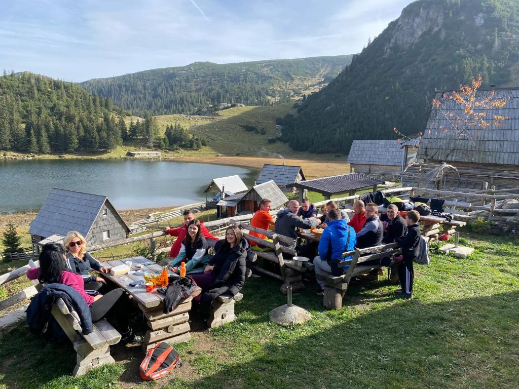 a group of people sitting at picnic tables on a hill at Zlatna koliba Namir Zuka in Fojnica
