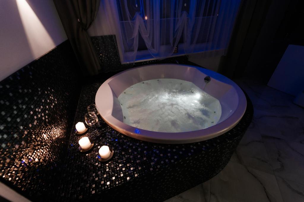 a bathroom with a tub with candles in it at Kiss Apartment in Šilutė
