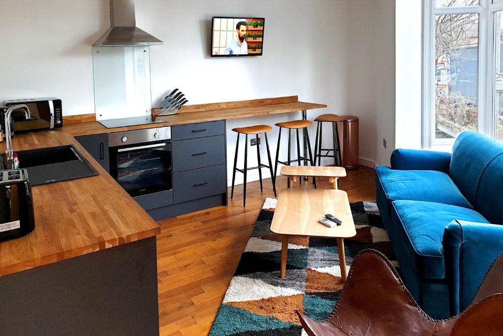 索爾泰爾的住宿－Salts House - Contemporary Apartments in Saltaire - Free On-Street Parking，一间带蓝色沙发的客厅和一间厨房