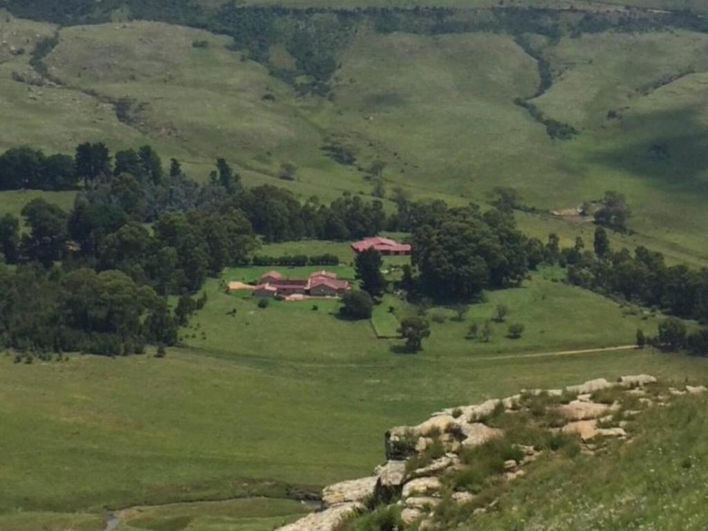 un champ vert avec une maison au-dessus dans l'établissement Mvemve Lodge at GrootPoort, à Memel