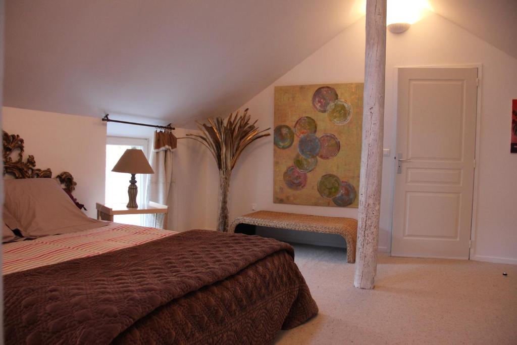 a bedroom with a bed and a painting on the wall at Domaine du Moulin de l'Etang in Châtillon-sur-Marne