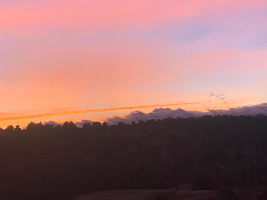 una puesta de sol con árboles y nubes en el cielo en Los Diezmos, en Jabaloyas