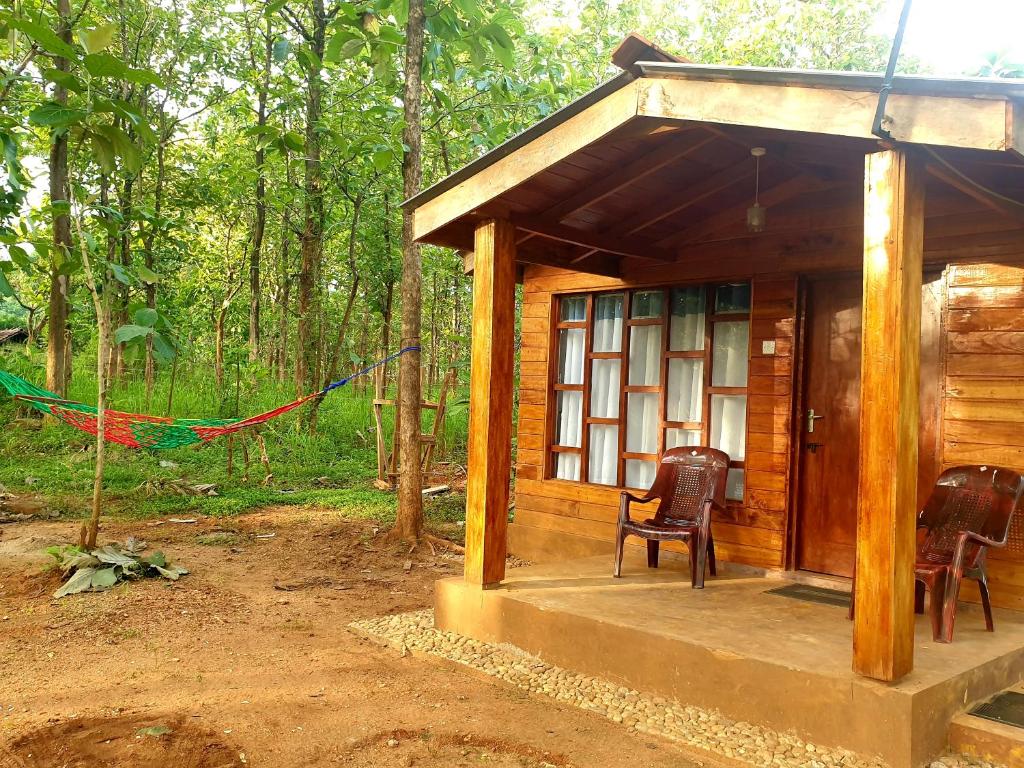 Cabaña de madera pequeña con 2 sillas en un bosque en Mini Jungle Canopy Udawalawe, en Udawalawe