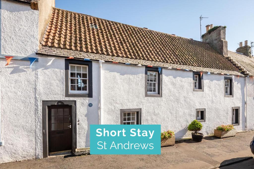 a white house with a sign that says short stay st alphavers at The Cooperage Garden Apartment - 1 bed-1 bath - near harbour in Crail