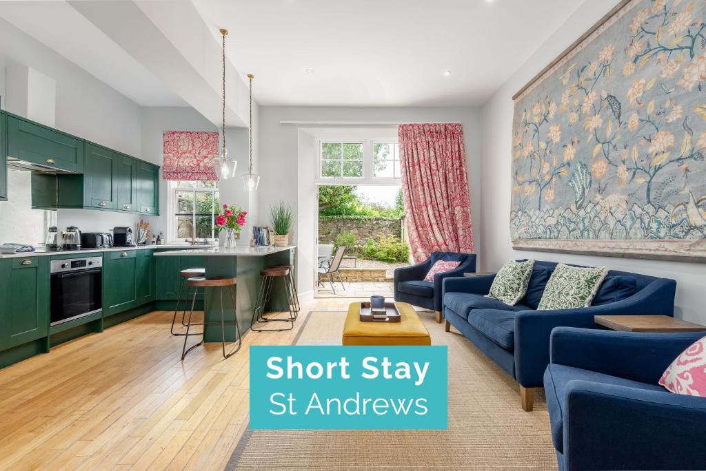 a living room with a blue couch and a kitchen at Greyfriars Bothy - Luxury Central 2 Bed Apartment in St. Andrews