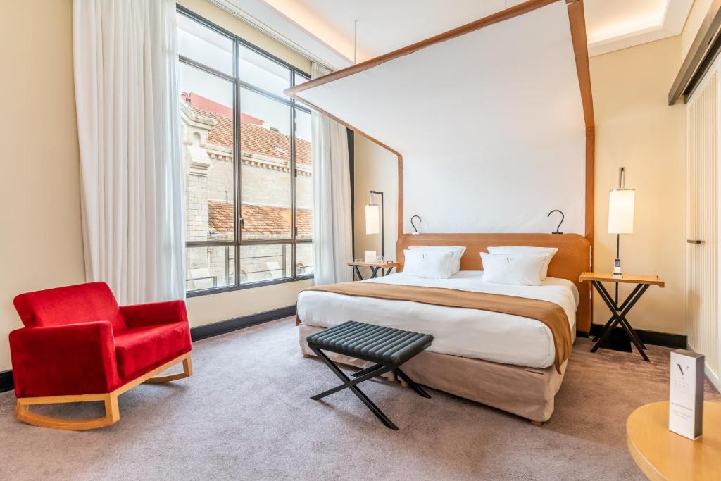 a bedroom with a large bed and a red chair at Five Seas by Inwood Hotels in Cannes