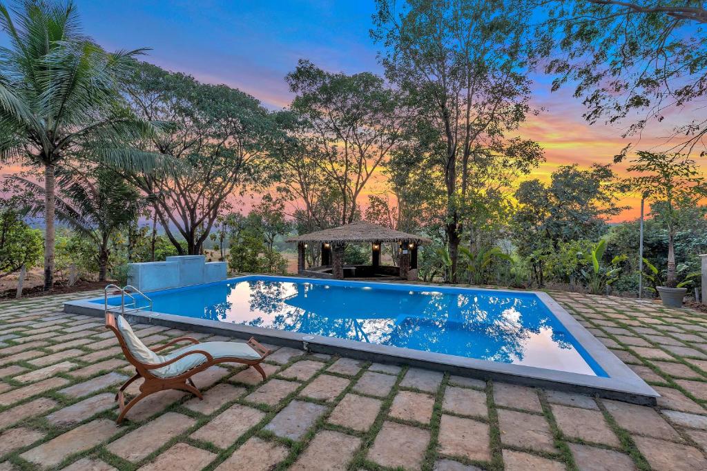 a swimming pool with a chair and a gazebo at SaffronStays Laburnum House, Wada - Palghar in Wada