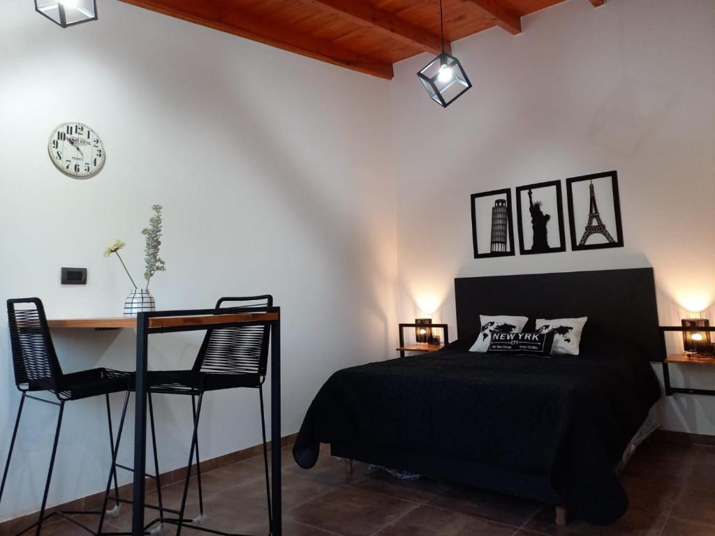 1 dormitorio con cama, escritorio y reloj en Departamento 2448, en Mina Clavero