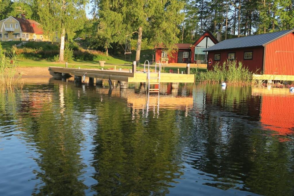 a dock on a lake next to a red building at Lovely house on beautiful private lakeside estate! 