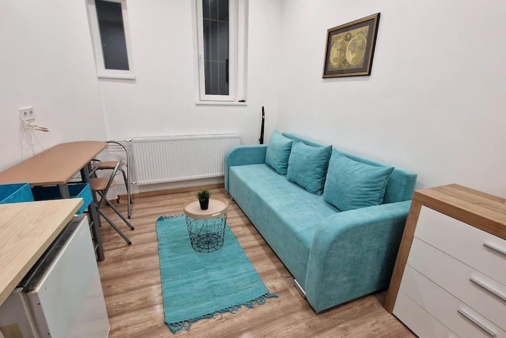 een woonkamer met een blauwe bank en een tafel bij Mini apartman in the central in Boedapest