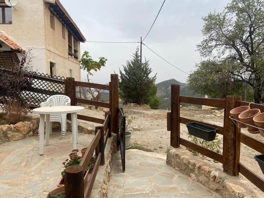 einen weißen Tisch und einen Stuhl auf einer Terrasse mit einem Zaun in der Unterkunft Preciosa casita rural en la sierra de Segur a, Cazorla y las Villas in Santiago-Pontones