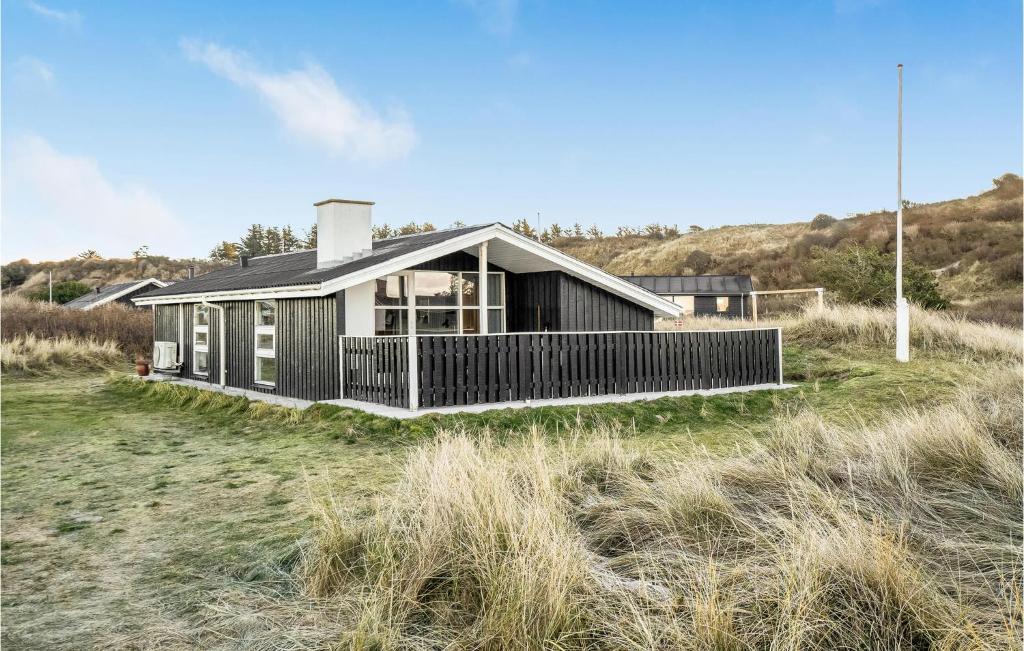 a black house on the beach with a field at Nice Home In Hjrring With Kitchen in Lønstrup