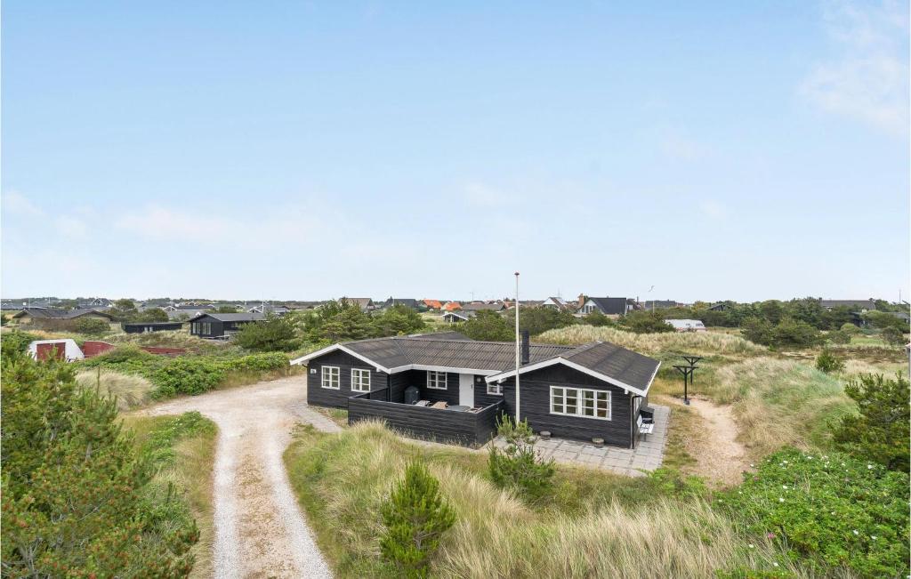 a house in a field with a dirt road at Three-Bedroom Holiday Home In Skagen in Skagen