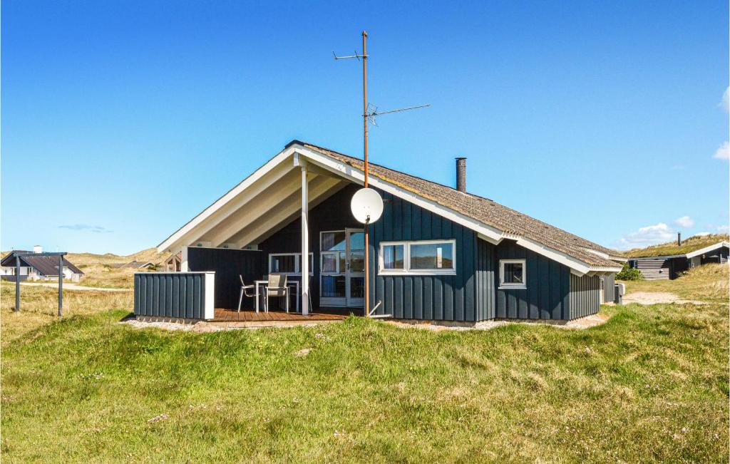 a small blue house on a grass field at Amazing Home In Ringkbing With 3 Bedrooms, Sauna And Wifi in Søndervig