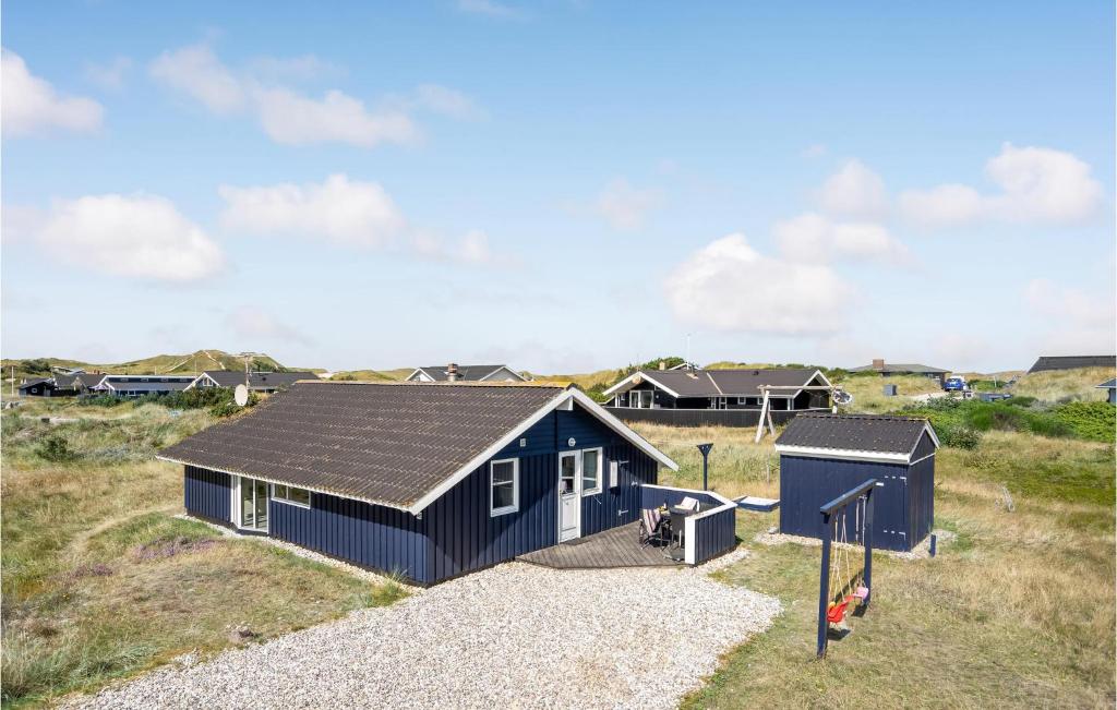 a blue house with a black roof and a playground at Amazing Home In Hvide Sande With Sauna in Havrvig