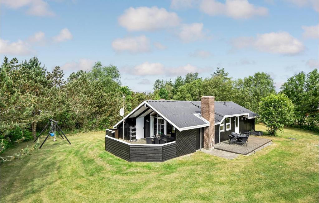 uma pequena casa negra num campo de relva em Amazing Home In Blvand With Wifi em Blåvand