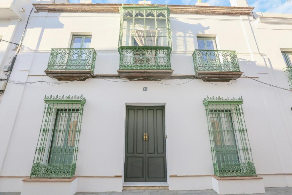 CASA SEÑORIAL CON PISCINA. CASA DONNA ISABEL في Peñaflor: مبنى أبيض بأبواب خضراء ونوافذ