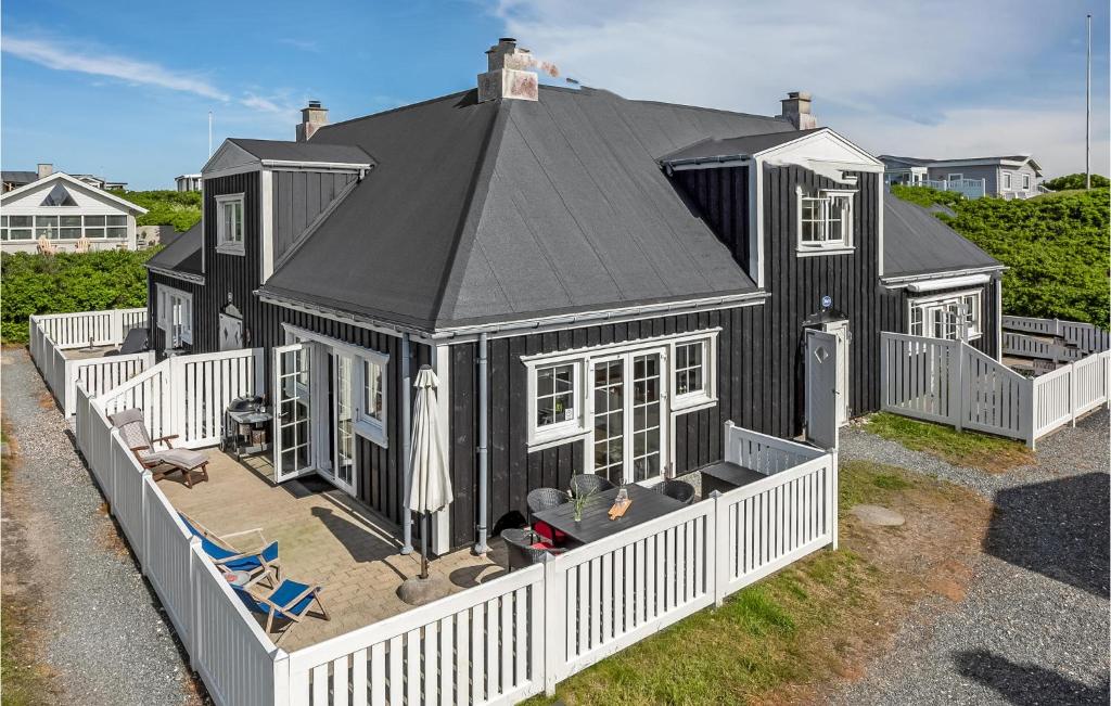 a black house with a white fence in front of it at Klitten in Søndervig