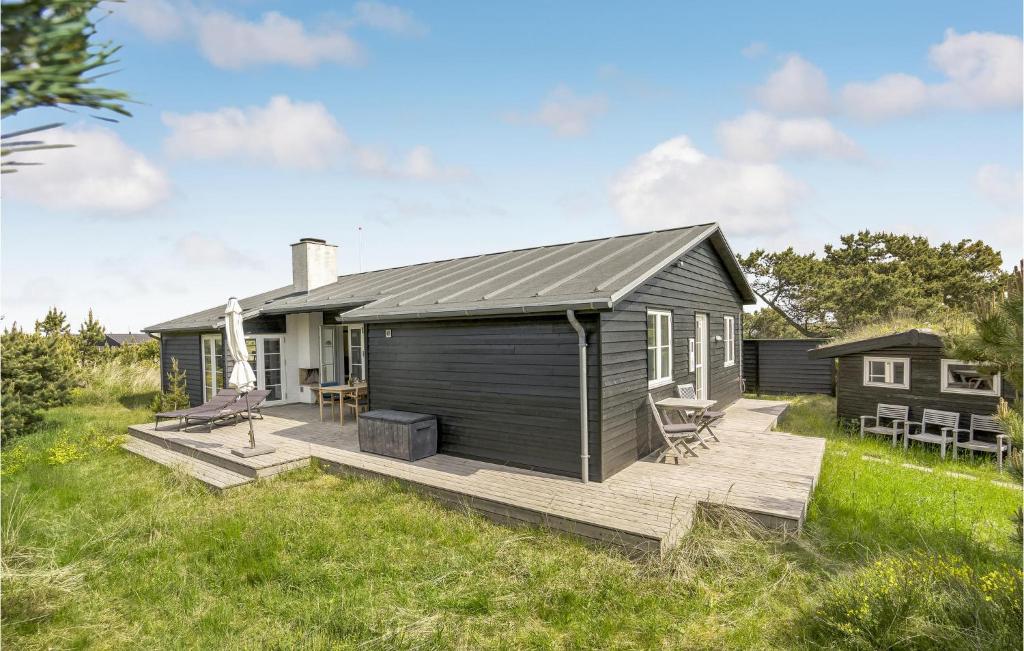 una casetta con un ponte in un campo di Three-Bedroom Holiday Home In Vejers Strand a Vejers Strand