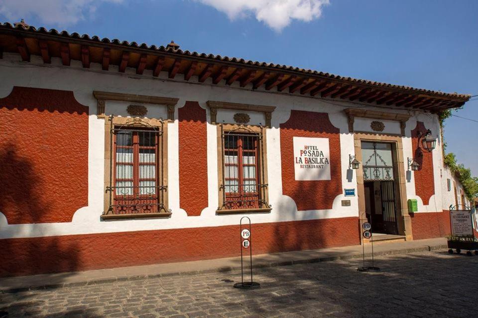 a red and white building with windows on a street at Hotel Boutique Posada La Basilica in Pátzcuaro