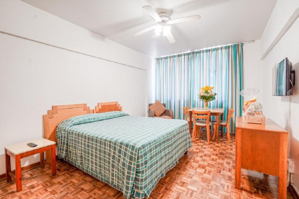 a bedroom with a bed and a table with a chair at Impala Holiday Flats & Apartments in Durban