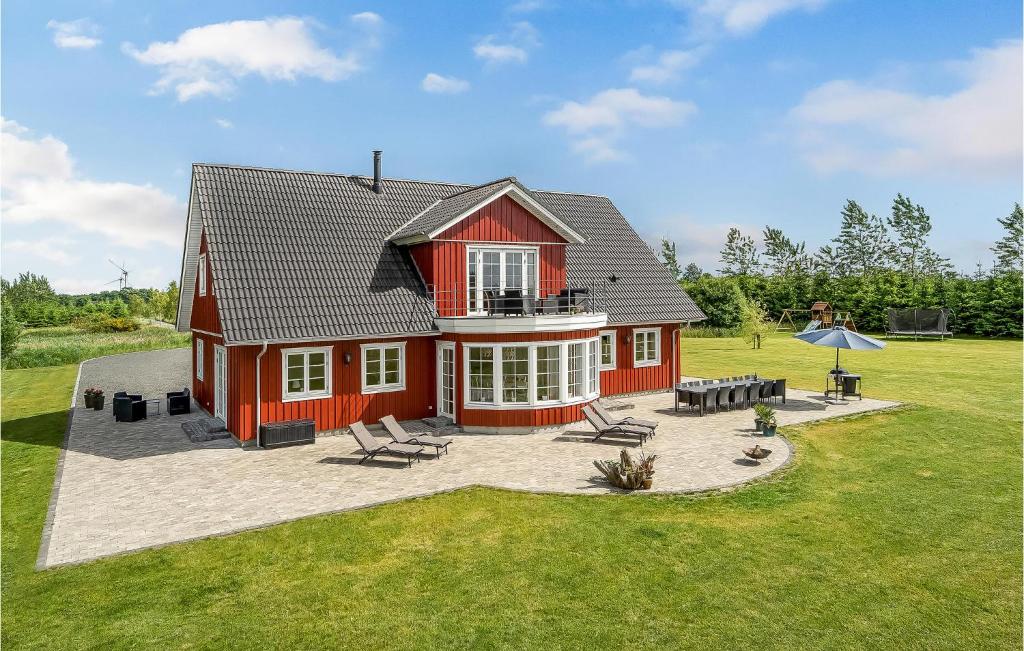 ein rotes Haus mit einer Terrasse im Hof in der Unterkunft Nice Home In Grindsted With House A Panoramic View in Grindsted