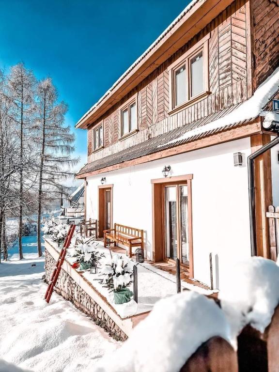 una casa en la nieve con porche en Góralska Chata en Czarna Góra