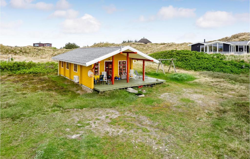 een klein geel huis op een grasveld bij Hoejris Hus in Søndervig