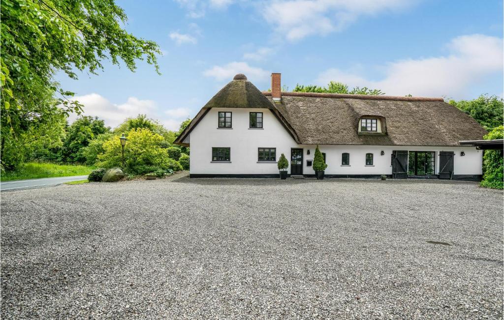 a white house with a thatched roof on a driveway at Nice Home In Sjlund With Kitchen in Sønder Bjert