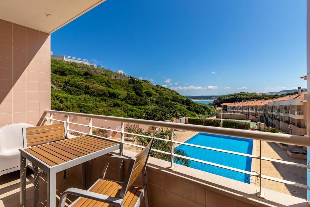 uma varanda com uma mesa e cadeiras e uma piscina em Bay View-T1 em São Martinho do Porto