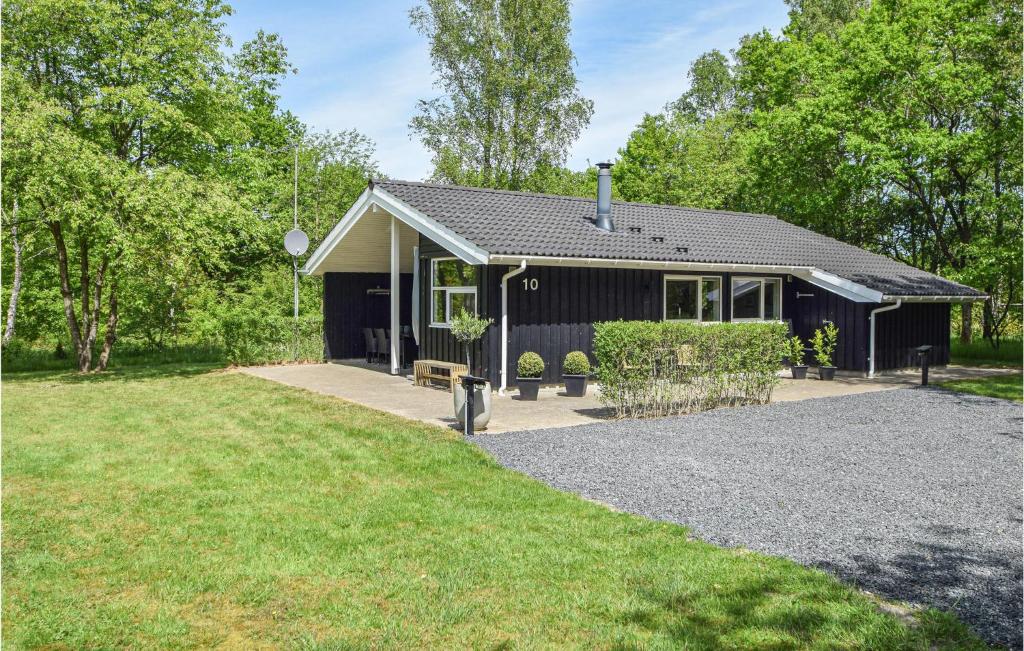 a black house with a gravel driveway in front of it at Nice Home In Give With 3 Bedrooms, Sauna And Wifi in Lindet
